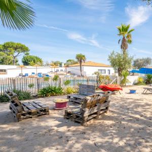 two wooden chairs and a table on the beach at Camping A la Corniche - Maeva in Angoulins-sur-Mer