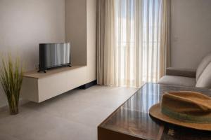 a living room with a television and a hat on a table at Comfortable ! Stylish ! Fully Air Conditioned ! in Sannat