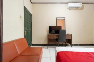 a room with a couch and a tv and a mirror at RedDoorz Syariah near Pasar Pagi Samarinda in Samarinda