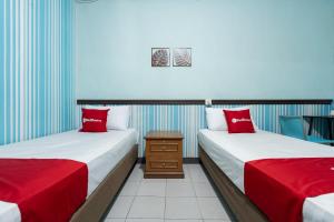 two beds in a room with red pillows at RedDoorz Syariah near Pasar Pagi Samarinda in Samarinda +29 photos