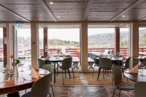 a dining room with tables and chairs and windows at Kuringen Brygge Hotel and Restaurant in Refsnes