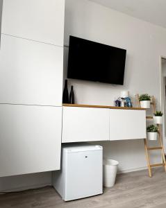a white entertainment center with a tv on a wall at Solo by Zirwick Apartment in Weiherhammer