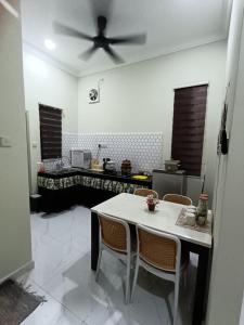 a kitchen with a table and a ceiling fan at Airisafiq Homestay in Kampong Sungai Rambai