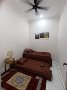 a bedroom with a bed and a ceiling fan at Airisafiq Homestay in Kampong Sungai Rambai +1 photo