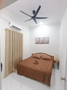a bedroom with a bed with a ceiling fan at Airisafiq Homestay in Kampong Sungai Rambai