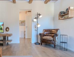 a living room with a leather chair and a floor lamp at Central City Apartment 2 with Mountain View in Zweisimmen
