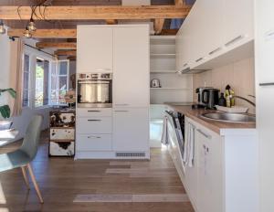 a kitchen with white cabinets and a sink at Central City Apartment 2 with Mountain View in Zweisimmen