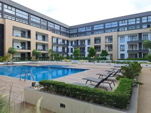 an exterior view of a building with a swimming pool at Oasis Apartments Gh by Embassy Gardens in Accra