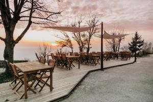 a wooden deck with tables and chairs and a sunset at Penzion Sinji vrh in Zoll