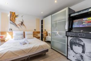 a bedroom with a bed and a flat screen tv at Jacuzzi 38C Sauna Privé - Climatisation in Furdenheim