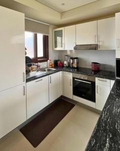 a kitchen with white cabinets and a black appliance at Sifa Golf & Beach Escape in As Sīfah