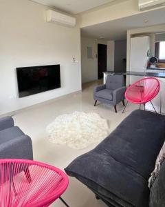 a living room with a black couch and pink chairs at Sifa Golf & Beach Escape in As Sīfah