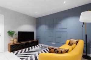 a living room with a yellow couch and a tv at Oasis Apartments Gh by Embassy Gardens in Accra