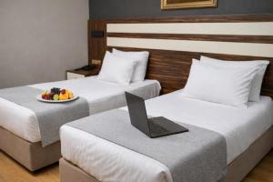 a hotel room with two beds with a laptop on a table at Akgün Hotel Laleli Istanbul in Istanbul