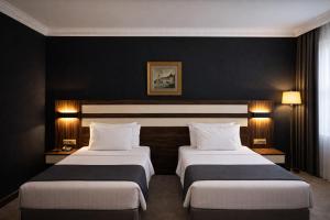 two beds in a hotel room with black walls at Akgün Hotel Laleli Istanbul in Istanbul