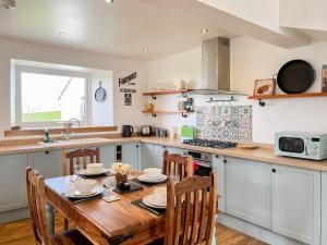 a kitchen with a wooden table with chairs and a sink at The Cheese Loft in Drummore