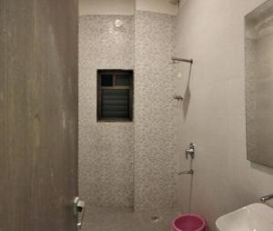 a bathroom with a shower with a toilet and a window at Mannat Bungalow in Amrāvati