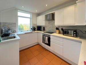 a kitchen with white cabinets and a orange tile floor at Holly Croft in Drem