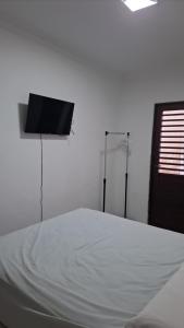 a bedroom with a bed and a flat screen tv at Suíte Tranquila em Ambiente Familiar em Antares in Maceió
