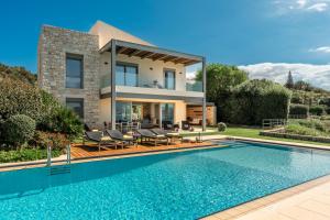 a villa with a swimming pool in front of a house at SK Place Luxury Seafront Villas Chania in Almyrida