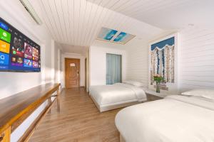 a hotel room with two beds and a flat screen tv at YISHUYIHUACoFFee Hotel in Zhangjiajie