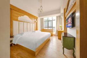 a bedroom with a large white bed and a television at YISHUYIHUACoFFee Hotel in Zhangjiajie