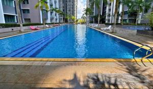 a large blue swimming pool in a building with palm trees at Almyra cozy condo in Kajang