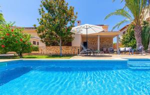 a swimming pool in front of a house with an umbrella at Mirte in Sa Coma