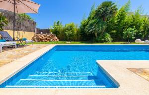 a swimming pool with blue water and an umbrella at Mirte in Sa Coma