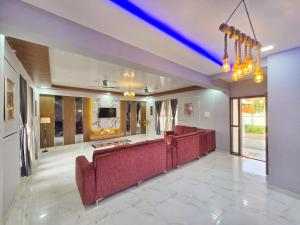 a living room with red couches and a tv at ll EMPYREAN STAYS ll SUPREME VILLA II 3BHK II AC II PVT POOL II MINI BAR in Lonavala