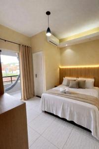 a bedroom with a large bed and a large window at Pousada Praia Dos Encantos in Japaratinga