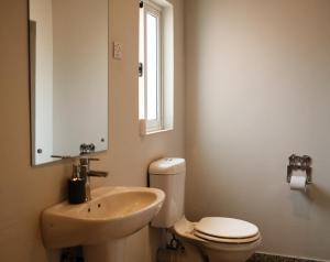 a bathroom with a sink and a toilet and a mirror at Jollyboys Backpackers and Camp in Livingstone