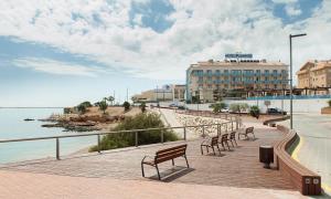 a row of benches on a boardwalk near the water at Hotel Flamingo in L'Ampolla