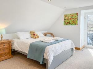 a teddy bear sitting on a bed in a bedroom at The Cheese Loft in Drummore