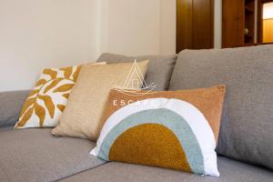 a couch with two pillows on it with a rainbow pillow at Anavrin by Escape to Madeira in Ponta do Sol