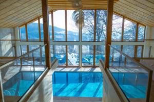 an indoor swimming pool with glass walls and a ceiling at The Cliff Village in Comarnic