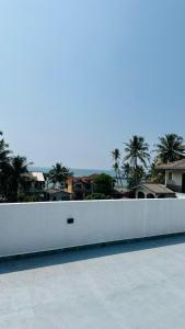 a white fence with palm trees in the background at Jameens Residence in Ambalangoda