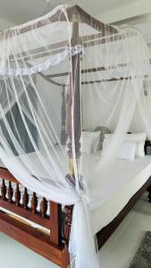a canopy bed with white mosquito nets on it at Jameens Residence in Ambalangoda