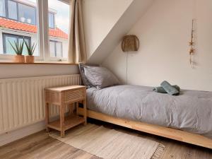 a bed in a room with a table and a window at Beach House Sea-Esta in Egmond aan Zee