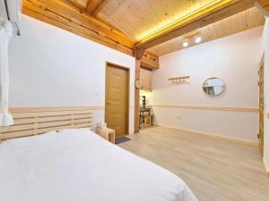 a bedroom with a white bed and a wooden ceiling at 나들한옥 한옥스테이 in Gyeongju