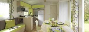 a kitchen with a table and a kitchen with green cabinets at Camping Etennemare in Saint-Valery-en-Caux