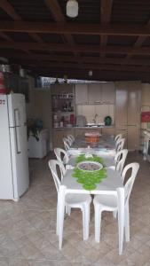 a kitchen with a table and white chairs and a refrigerator at 500 metros da praia in Governador Celso Ramos