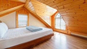 a bed in a room with wooden walls and windows at Ganghwa Western Beach Pension in Incheon