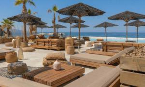 a resort with benches and umbrellas on the beach at Maya Beach Resort in Massa Lubrense