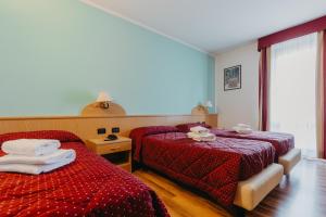 a hotel room with two beds and a window at Hotel Spera in Strigno
