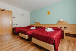 two beds in a room with red comforter at Hotel Spera in Strigno