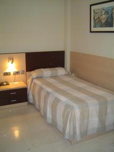 a hotel room with a bed and a night stand at Hotel Flamingo in L'Ampolla