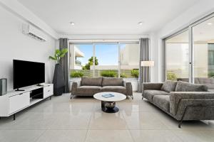 a living room with two couches and a tv at Levanda Hills Haven in Protaras in Paralimni