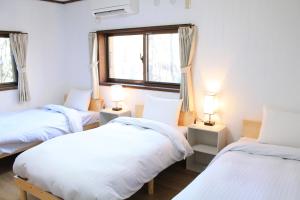 a room with three beds and two windows at 彩の宿月屋 in Yamanakako