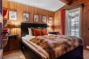 a bedroom with wooden walls and a large bed with a faux fur blanket at TH589- Large ski-in out chalet in Trysilfjell with sauna, hottub in Hovi